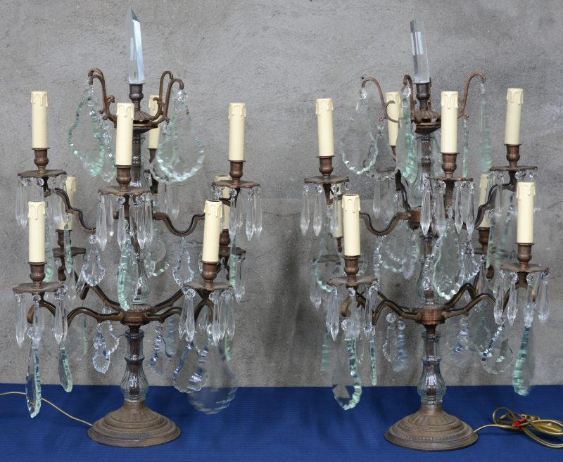 Een paar bronzen girandoles met acht lichtpunten in twee niveaus en met kristallen pendeloques.