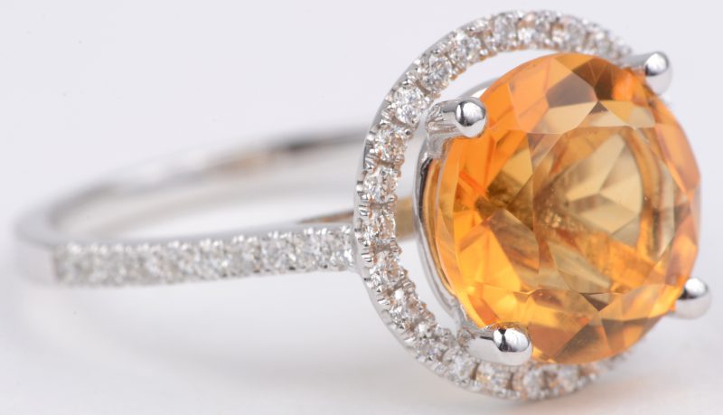 Een 18 karaats wit gouden ring bezet met diamanten met een gezamenlijk gewicht van ± 0,35 ct. en een centrale smaragd van ± 3,35 ct.