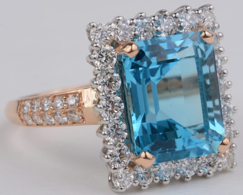 Een 18 karaats wit en rooskleurige gouden ring bezet met diamanten met een gezamenlijk gewicht van ± 1,36 ct. en een Zwitserse topaas van ± 7,57 ct.