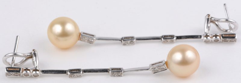 Een paar 18 karaats wit gouden oorbellen bezet met diamanten met een gezamenlijk gewicht van ± 0,45 ct. en parels.