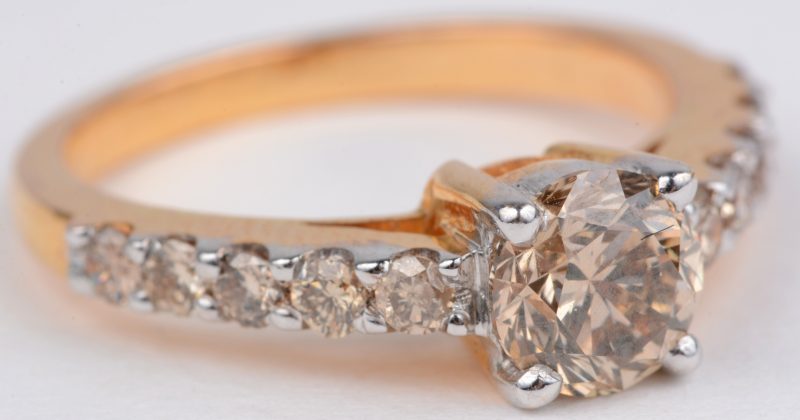 Een 18 karaats wit en rooskleurige gouden ring bezet met 10 cognackleurige briljanten met een gezamenlijk gewicht van ± 0,20 ct. en een centrale cognackleurige diamant van ± 0,60 ct.