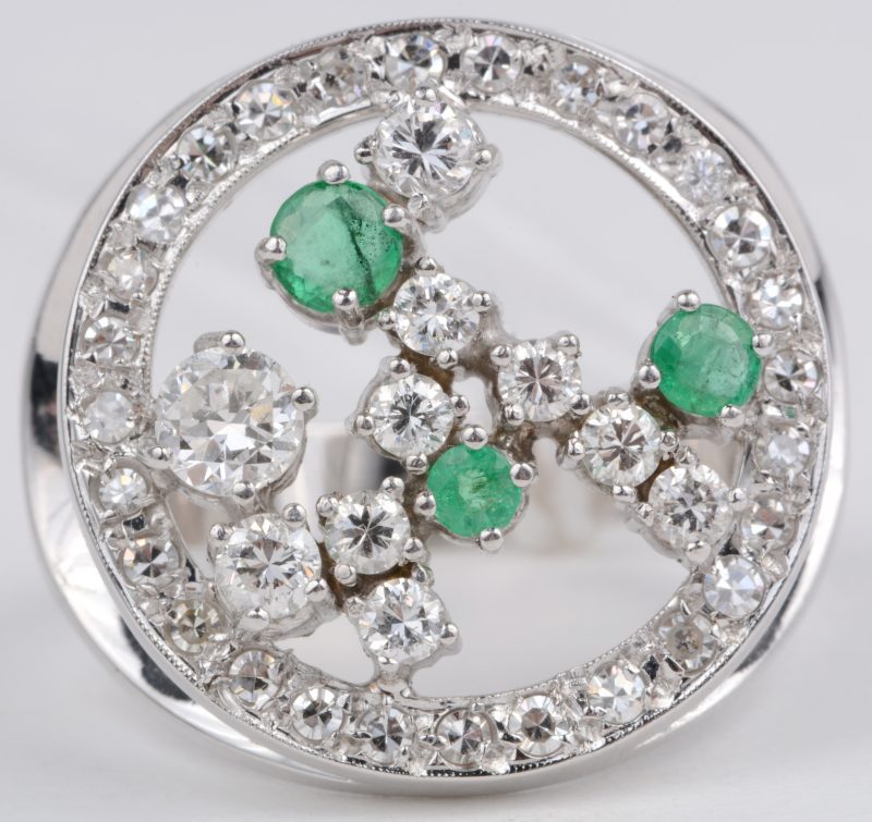 Een 18 karaats wit gouden ring bezet met diamanten met een gezamenlijk gewicht van ± 1,35 ct. en smaragden met een gezamenlijk gewicht van ± 0,30 ct.