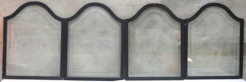 Vier glasramen van geslepen mat glas met een symbool van een hamer en een beitel.