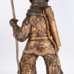 Een Chinese krijger van brons met meerkleurig patina op houten voetstuk.
