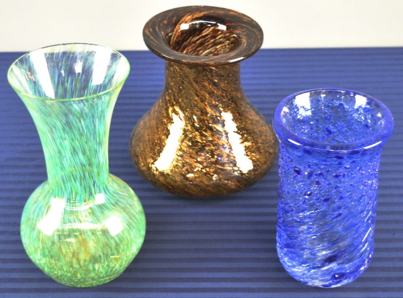 Drie verschillende vaasjes van glaspasta, resp. in bruin, blauw en groen.