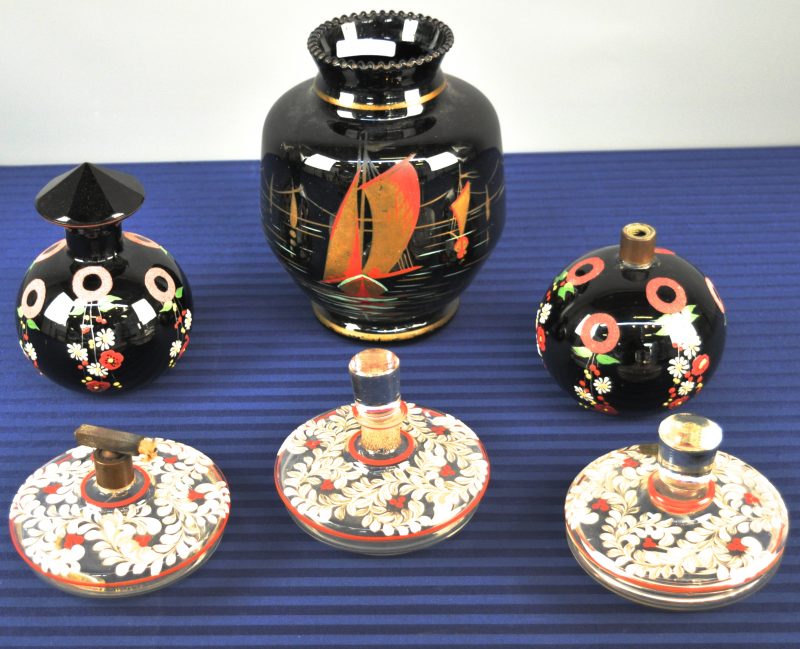 Een lot Booms glas, bestaande uit een grote vaas, een bol karafje en een parfumflesje van zwart glas en een driedelig toiletstelletje met handgeschilderde plantendecors.