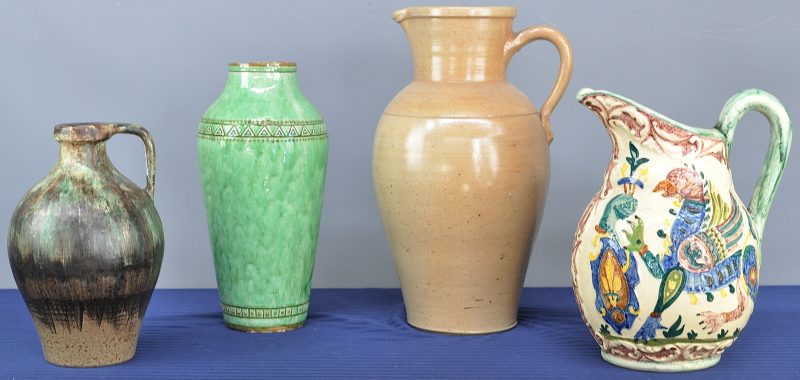 Een lot aardewerk, bestaande uit twee schenkkannen, een kruik en een vaas. De beige schenkkan met barst.