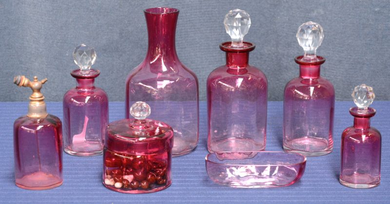 Een achtdelig toiletstel van mauve glas, waarbij de flesjes met kristallen stoppen.