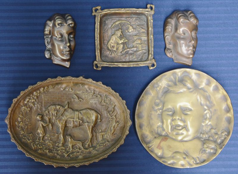 Vier verschillende bronzen asbakken met reliëfdecors, resp. met een voetballer, een pijproker, een stoomlijner en de Menenpoort te Ieper.