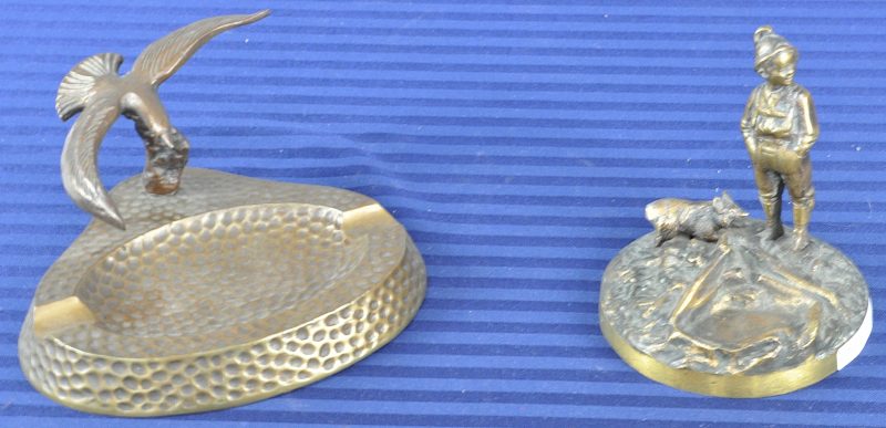 Een asbak en een schaaltje van brons, de eerste versierd met een zeevogel, de andere in de vorm van een jongetje met een hondje.
