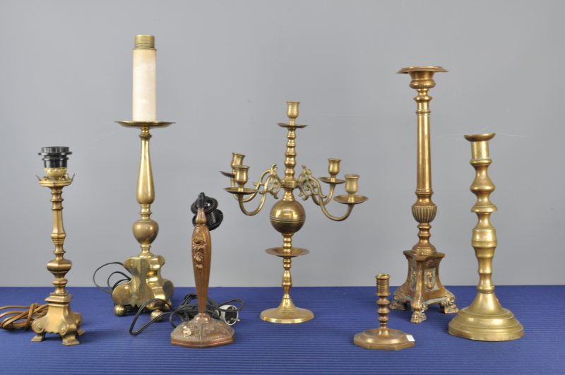 Een lot van zeven koperen kandelaars in verschillende maten en uitvoeringen, waarvan drie gemonteerd als lampenvoet.