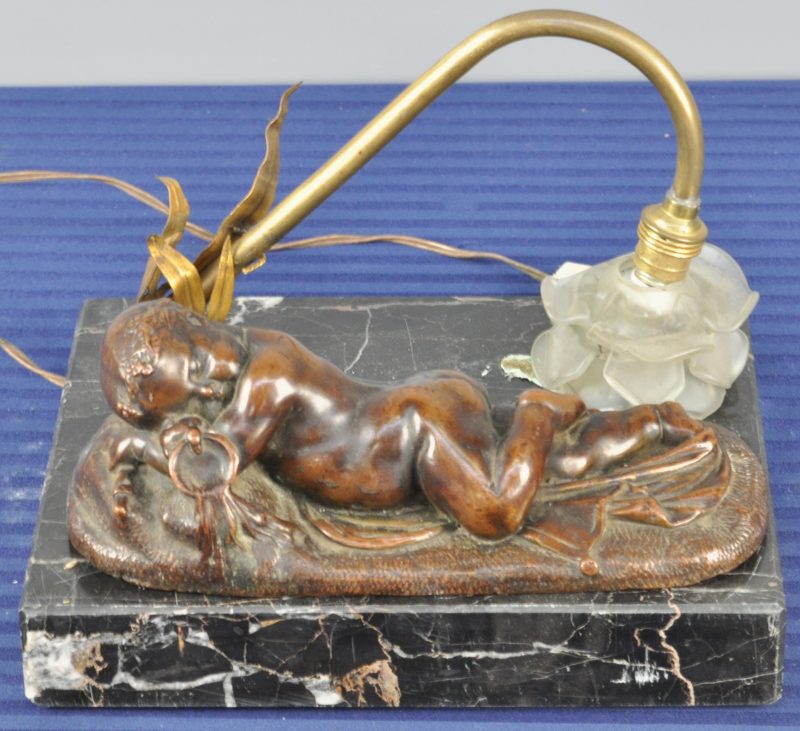 “Slapende Bacchus”. Een beeldje van met koper overtrokken gips naar een werk van Jaquet. Op marmeren sokkel met een bloemvormig lampje met glazen kapje. Te restaureren.