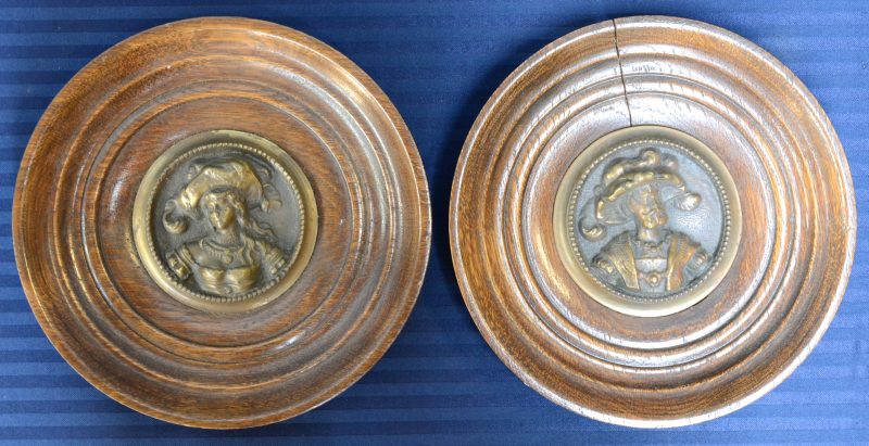 “Edele dame en heer”. Twee plaquettes van brons in hoogreliëf. In ronde houten lijsten.