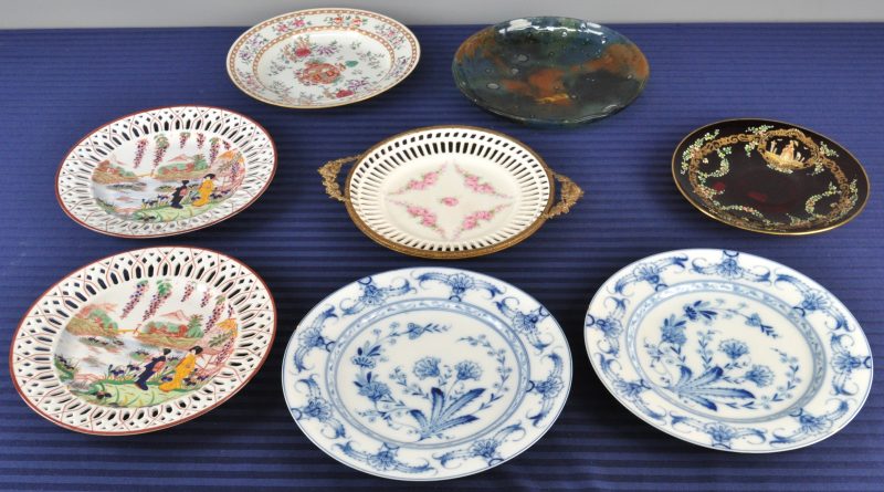 Een lot van acht borden, waaronder twee met een blauw en wit decor, twee met een Chinees decor, één opengewerkt en in koperen montuur, één met bloemendeocr, één van rood glas en één van glaspasta.