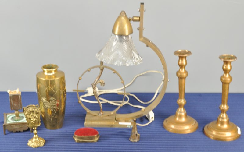 Een lot messing, bestaande uit een lamp met glazen kap en versierd met een vrouwelijk naakt, een Japanse vaas, twee kandelaars en twee luciferhouders.