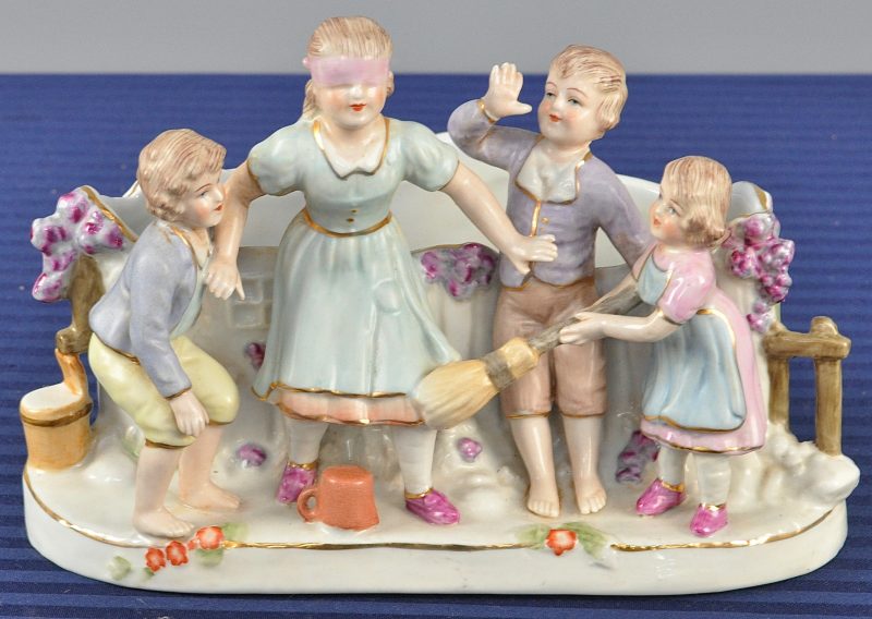Een sierjardinière van meerkleurig porselein in de vorm van vier spelende kindjes.