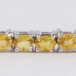 Een zilveren schakelarmband bezet met gele saffier met een gezamenlijk gewicht van ± 9 ct.