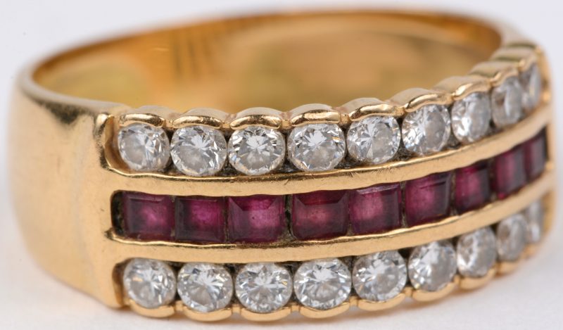 Een 18 karaats geel gouden ring bezet met briljanten met een gezamenlijk gewicht van ± 0,90 ct. en gekalibreerde robijn baguettes met een gezamenlijk gewicht van ± 0,45 ct.