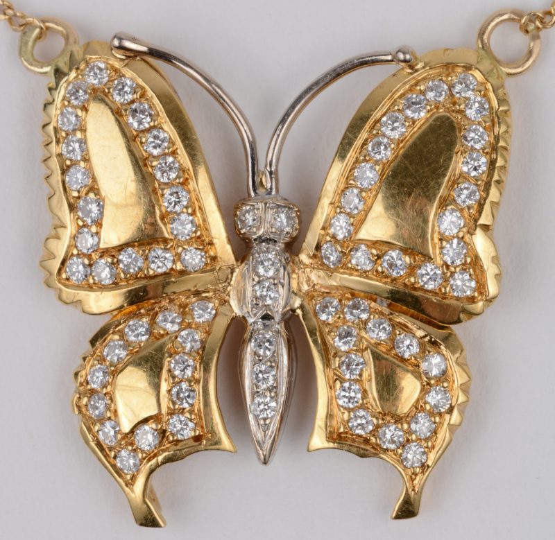 Een 18 karaats geel gouden ketting met hanger van 18 karaats wit en geel goud in de vorm van een vlinder bezet met briljanten met een gezamenlijk gewicht van ± 1,50 ct.