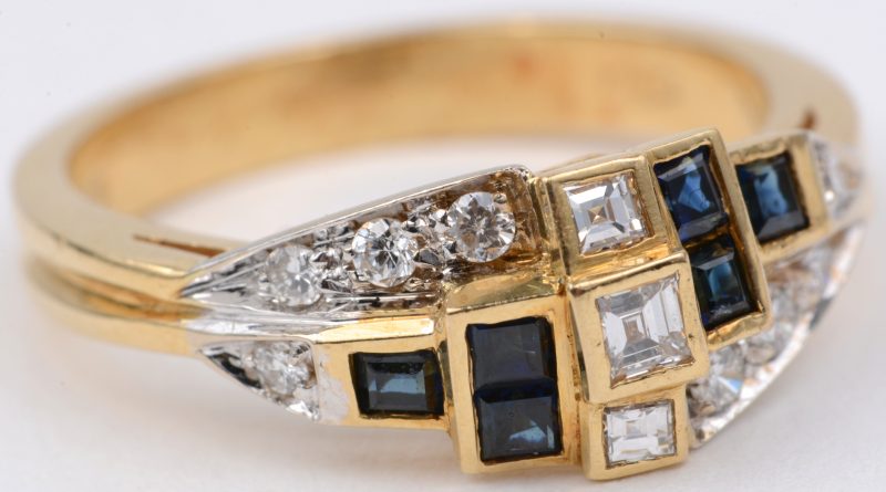 Een 18 karaats wit en geel gouden ring bezet met diamanten en baguettes met een gezamenlijk gewicht ± 0,40 ct en saffieren met een gezamenlijk gewicht van ± 0,4O ct.