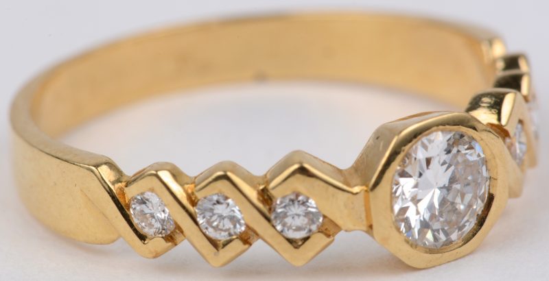 Een 18 karaats geel gouden ring bezet met een centrale diamant van ± 0,40 ct. en briljanten met een gezamenlijk gewicht van ± 0,30 ct.