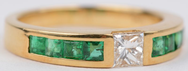 Een 18 karaats geel gouden ring bezet met een diamant in princesse geslepen van ± 0,40 ct. en smaragd baguettes met een gezamenlijk gewicht van ± 0,60 ct.