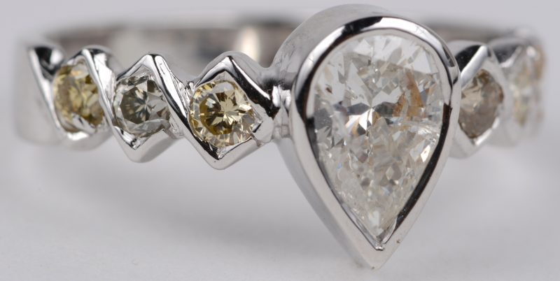 Een 18 karaats wit gouden ring bezet met een centrale peervormige diamant van ± 0,70 ct. en diamanten met een gezamenlijk gewicht van ± 0,60 ct.