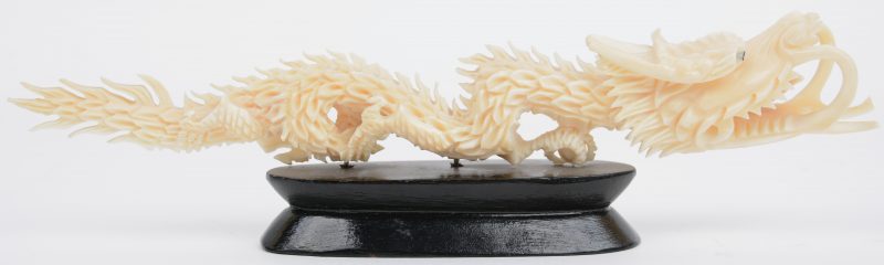 Een draak van fijn gesculpteerd ivoor. Chinees werk. Op houten sokkel. Begin XXe eeuw.