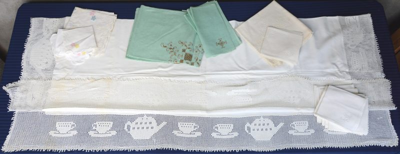 Drie verschillende tafelkleedjes met bijpassende servetten en één groot tafelkleed bezet met borduurwerk.