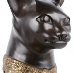 Een zittende kat van donkergeppatineerd brons met vergulde halsband. Naar een voorbeeld van Amerigo Tot.