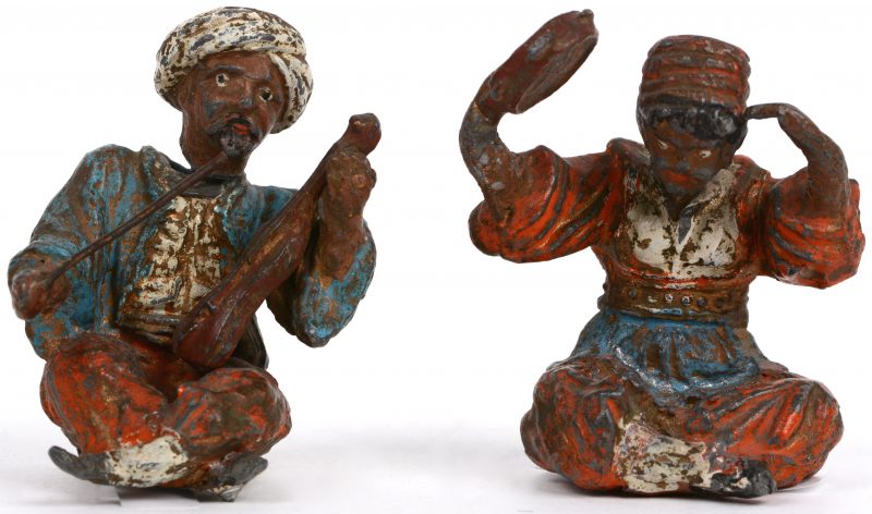 Twee figuurtjes van gepolychromeerd brons met wiebelende hoofdjes.