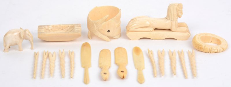 Een lot ivoor bestaand uit: een sfinx, vorkjes en vismessen, twee servetringen en een beschadigde olifant.