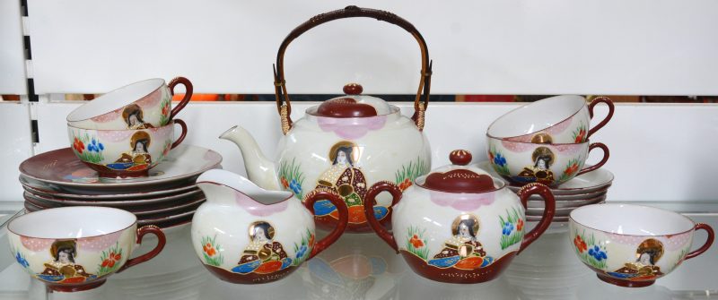 Een theeservies van meerkleurig porselein met een Satsumadecor, bestaande uit een theepot, melkpot, suikerpot, zes kopjes met schoteltjes en zes borden. Onderaan gemerkt.