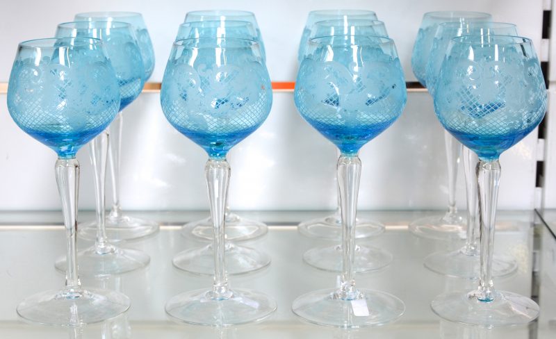 Een reeks van twaalf glazen van kleurloos en blauw kristal met een geslepen decor.