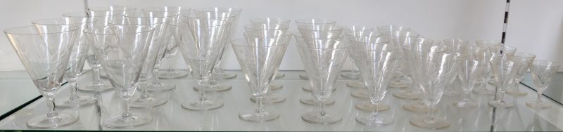 Een glazenservies van kleurloos kristal met een gegraveerd decor, bestaande uit twaalf likeurglaasjes, tien aperitiefglazen, acht wittewijnglazen en elf rodewijnglazen. Enkele kleine schilfers aan de rand.