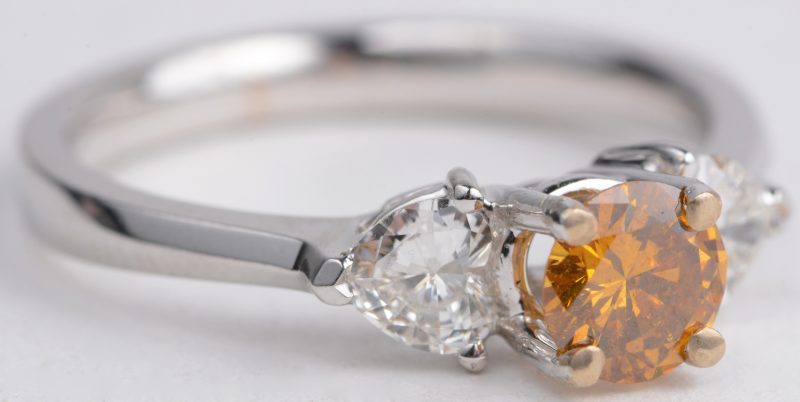 Een 18 karaats wit gouden ring bezet met twee hartvormige diamanten met een gezamenlijk gewicht van ± 0,35 ct. en een fancy diamant van ± 0,75 ct.