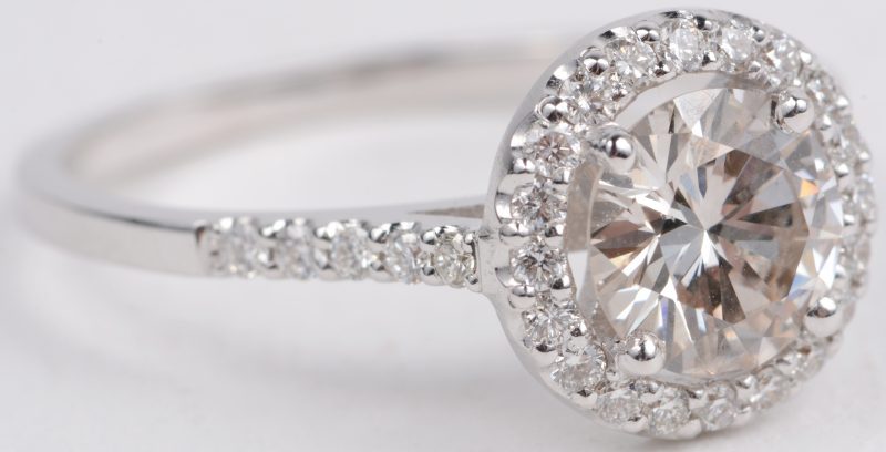 Een 18 karaats wit gouden ring bezet met een centrale diamant van ± 1 ct. en met diamanten met een gezamenlijk gewicht van ± 0,30 ct.
