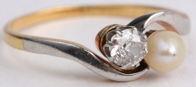 “Toi et moi”. Een 18 karaats wit en geel gouden ring bezet met één parel en één diamant van ± 0,20 ct.