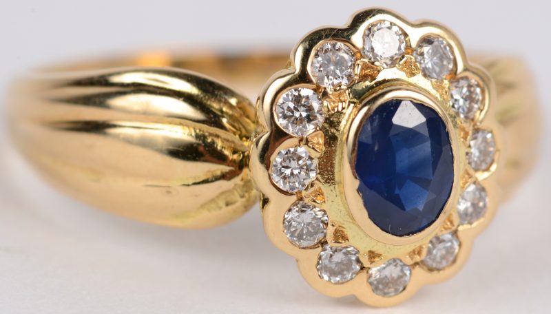 Een 18 karaats geel gouden ring bezet met briljanten met een gezamenlijk gewicht van ± 0,30 ct. en een saffier van ± 0,25 ct.