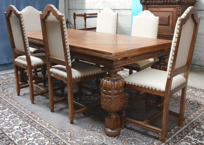 Een verlengbare tafel van gebeeldhouwd eikenhout met zes bijpassende stoelen.