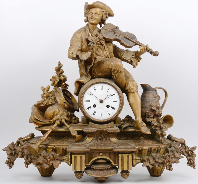 Pendule van verguld zamac met voorstelling van een violist. Omstreeks 1900. Wijzerplaat gemerkt Foucel (?). Horlogeglas ontbreekt. Compleet met slinger en sleutel.
