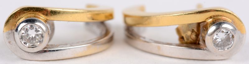 Een paar 18 karaats wit en geel gouden oorbellen bezet met diamanten met een gezamenlijk gewicht van ± 0,20 ct.