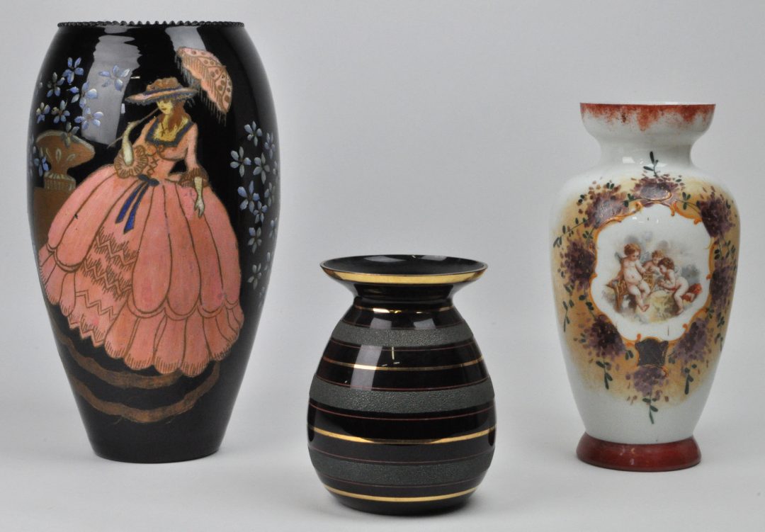 Een lot bestaande uit een zwarte vaas met een handgeschilderd decor van een dame, melkglazen vaas met een gedrukt decor van engeltjes en klein glazen vaasje van Doyen à Havré-Ville. – Jordaens N.V. Veilinghuis