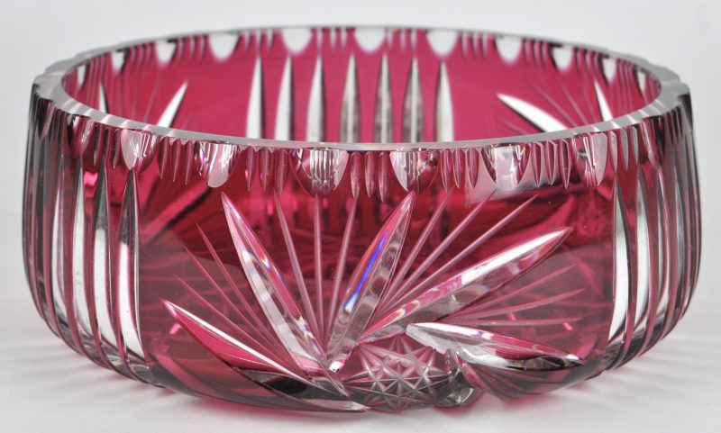 Een coupe van geslepen kristal, rood gekleurd in de massa.