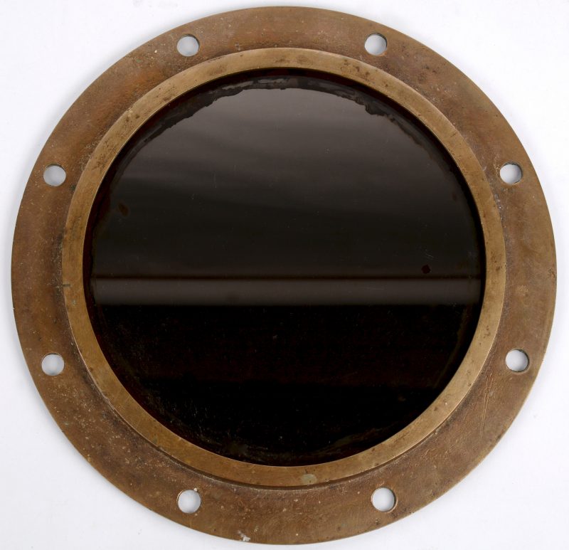 Een ronde spiegel, gemonteerd in een bronzen patrijspoort.