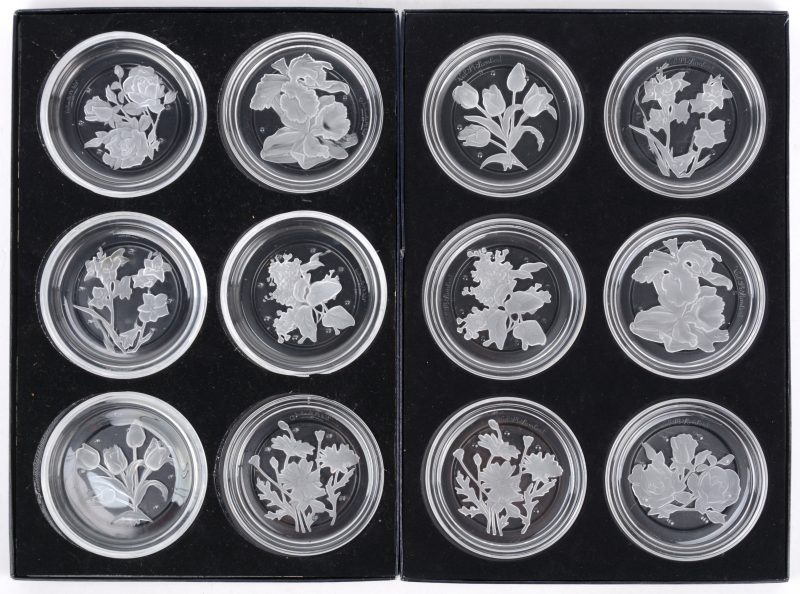 Twee series van zes onderzetters van kleurloos kristal met een gegraveerd decor van bloemen. In originele etuis.