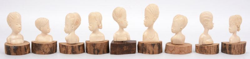 Een lot van negen kleine Afrikaanse vrouwenbustes van gesneden ivoor op houten sokkeltjes.