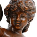 “Cupido”. Een beeld van bruingepatineerd brons op een beige marmeren voetstuk.