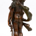 “Cupido”. Een beeld van bruingepatineerd brons op een beige marmeren voetstuk.