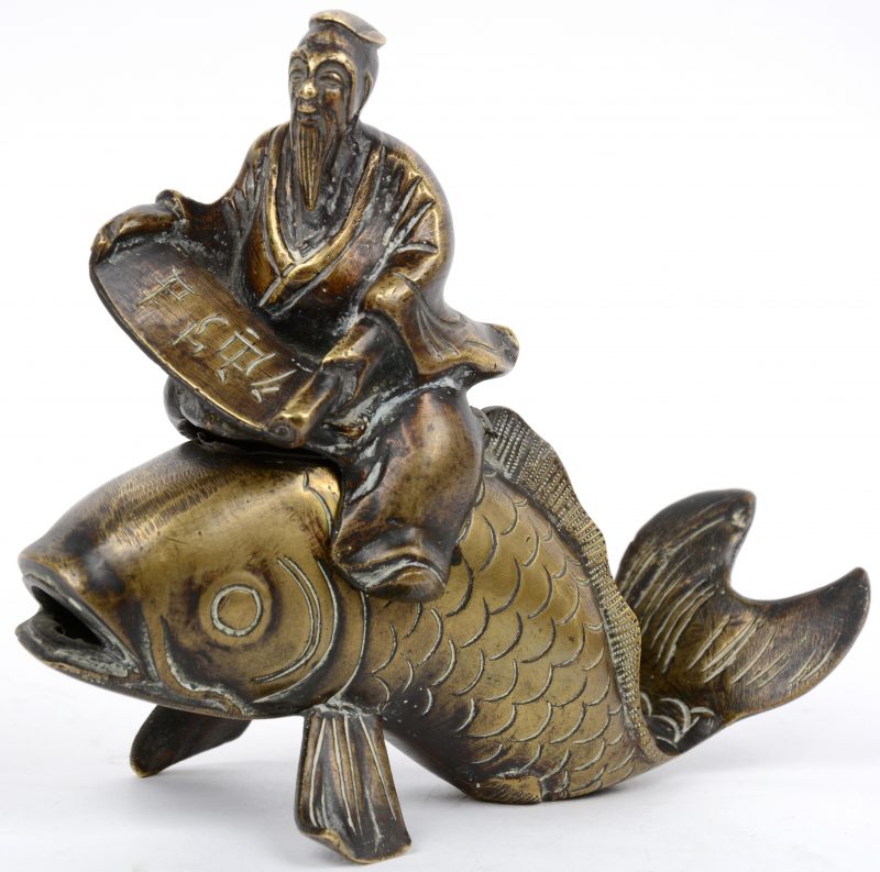 Een dekseldoosje van brons in de vorm van een oude wijze op een vis.